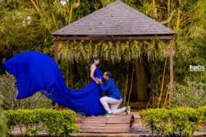 Maternity couple photoshoot with flowing blue gown in a garden